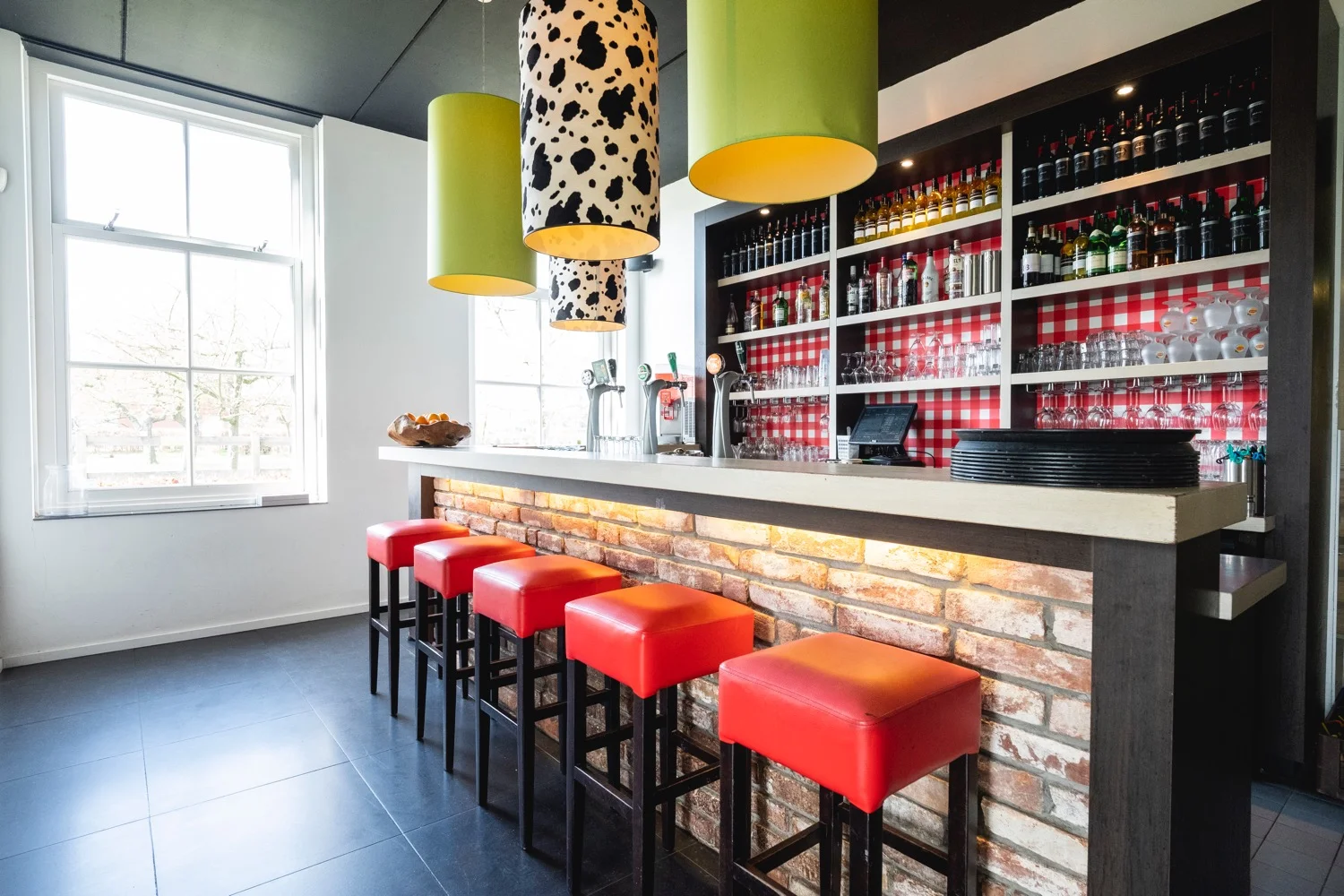 De bar met rode krukken en hanglampen met koeienprint