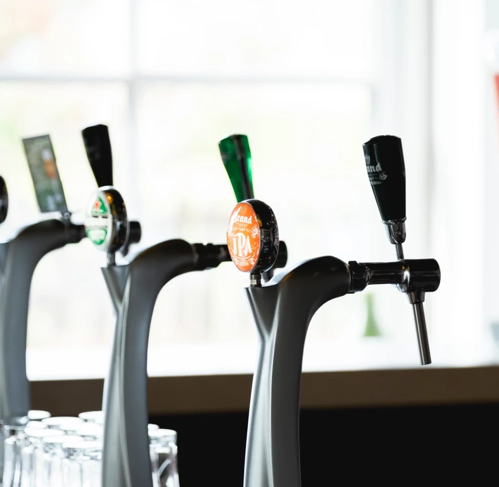 Drie biertaps op de bar, met daglicht op de achtergrond
