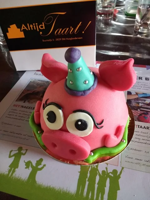 Zelfgemaakte boltaart in de vorm van een varken met een feestmuts