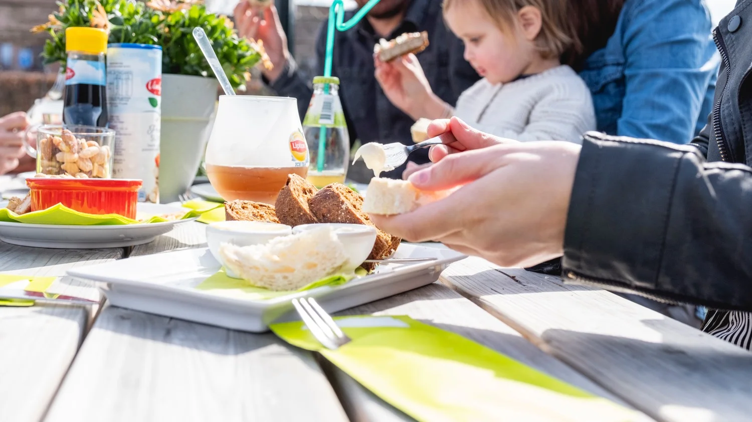 Gezin met jonge kinderen eet samen aan een lange tafel in het restaurant