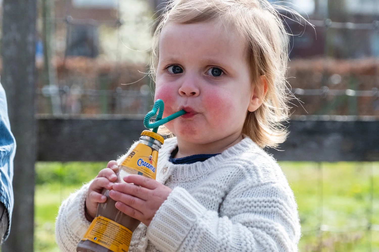 Peuter drinkt buiten uit een flesje in het gras