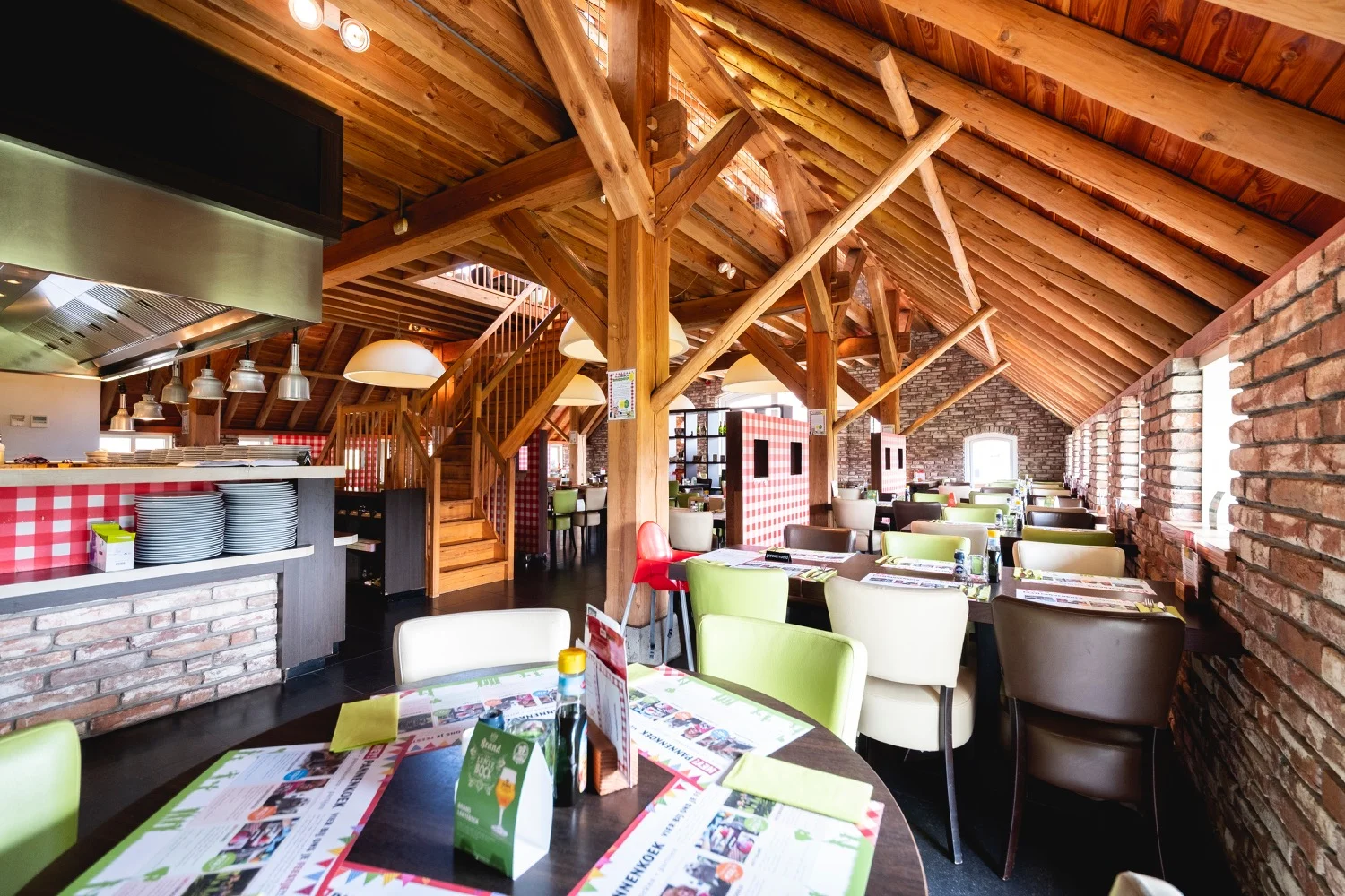 De restaurantzaal met de bar, groene stoelen en rood-wit geblokte accenten