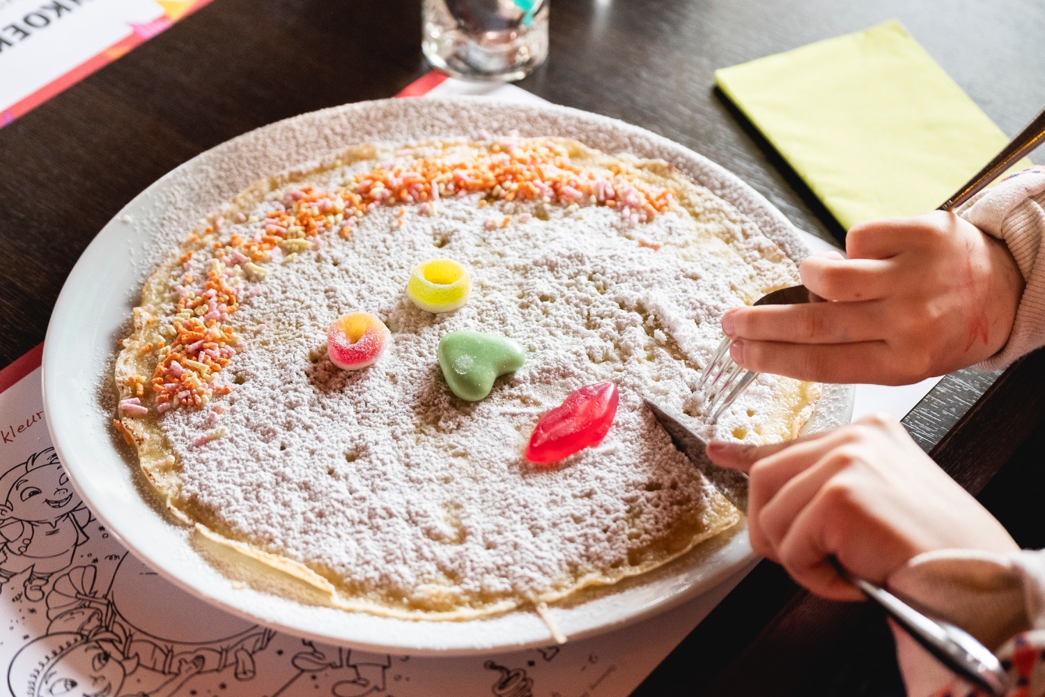 Kinderpannenkoek met poedersuiker en snoep, opgemaakt als een lachend gezicht
