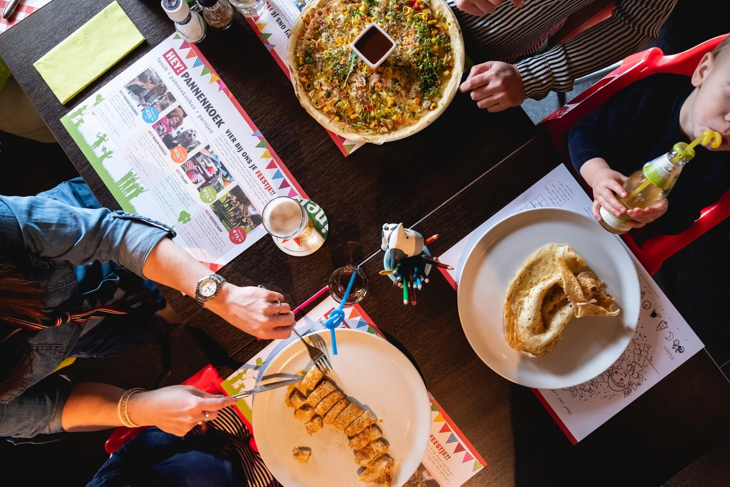 Tafel van bovenaf gezien met pannenkoeken, drinken en placemats