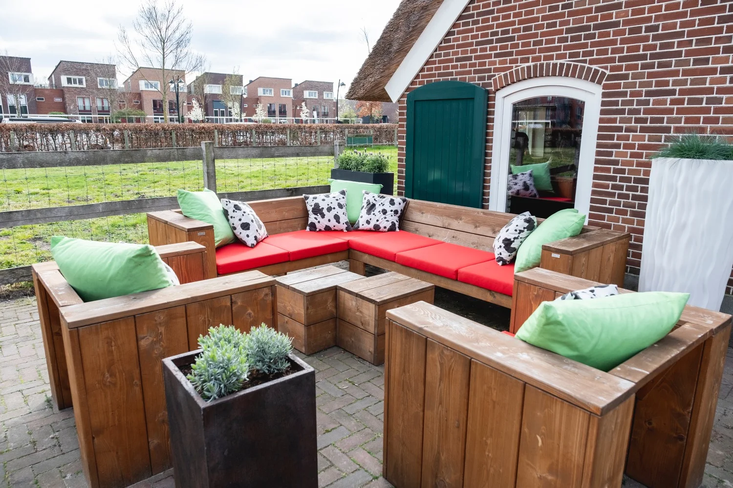 Terrasbank met rood-wit geblokte kussens tegen de gevel van de boerderij
